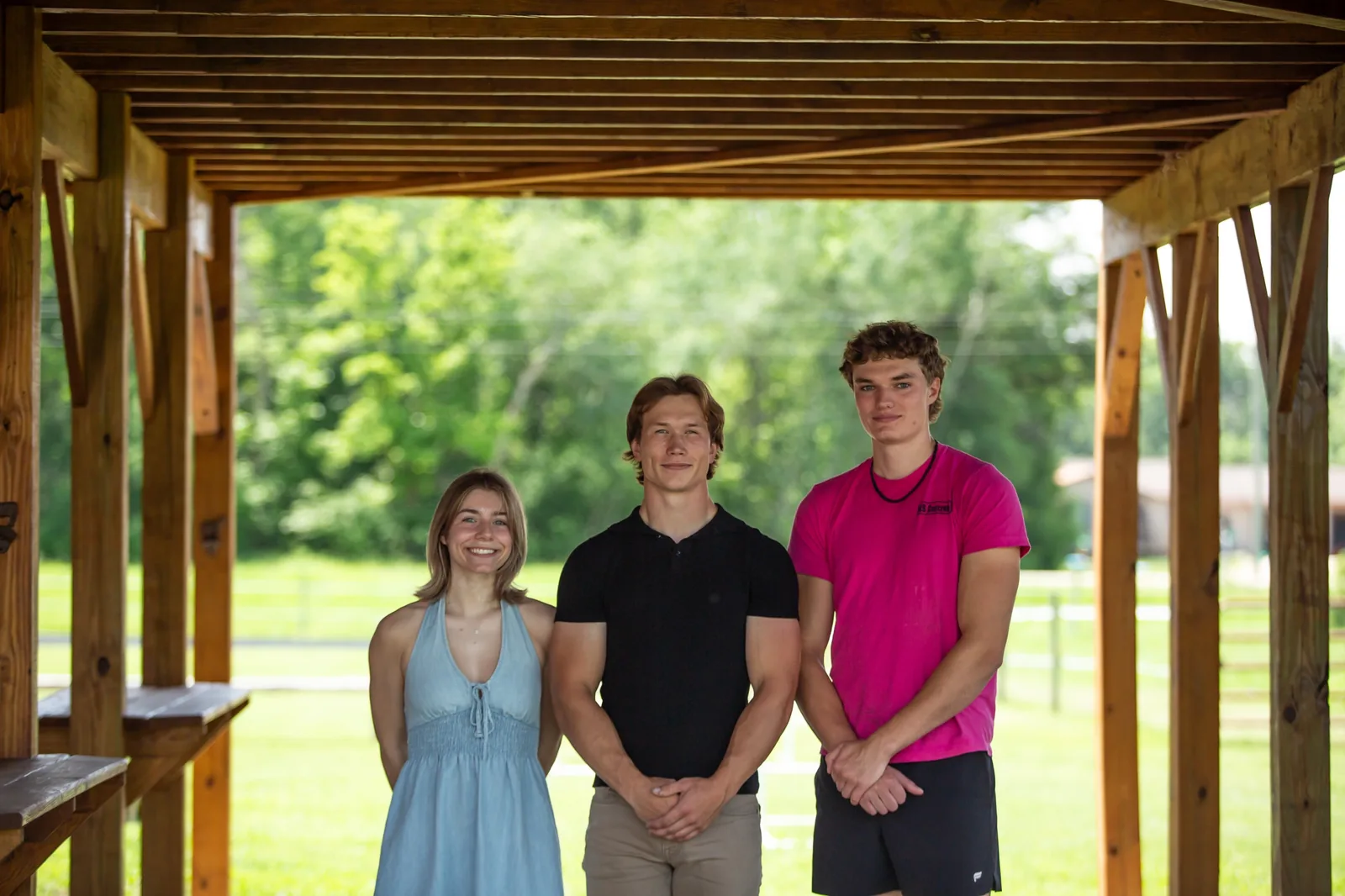 Brynn Hanson, Mason Schroeder, and Wesley Aspengren of WAMS Stylish Coatings standing under a wooden pergola