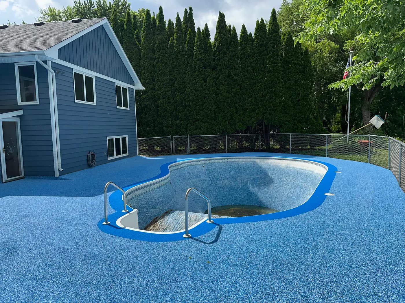 Blue RevaFlex pool deck with a brighter blue border outlining the pool, installed by WAMS