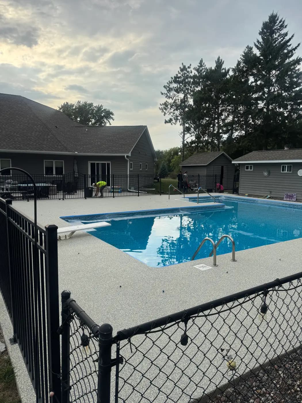 Gray RevaFlex pool deck inside a black metal fence, installed by WAMS