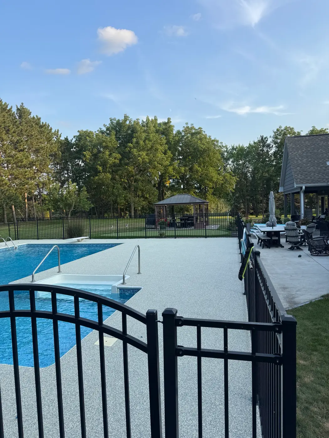 Gray RevaFlex pool deck with pool steps and a fenced yard beyond, installed by WAMS