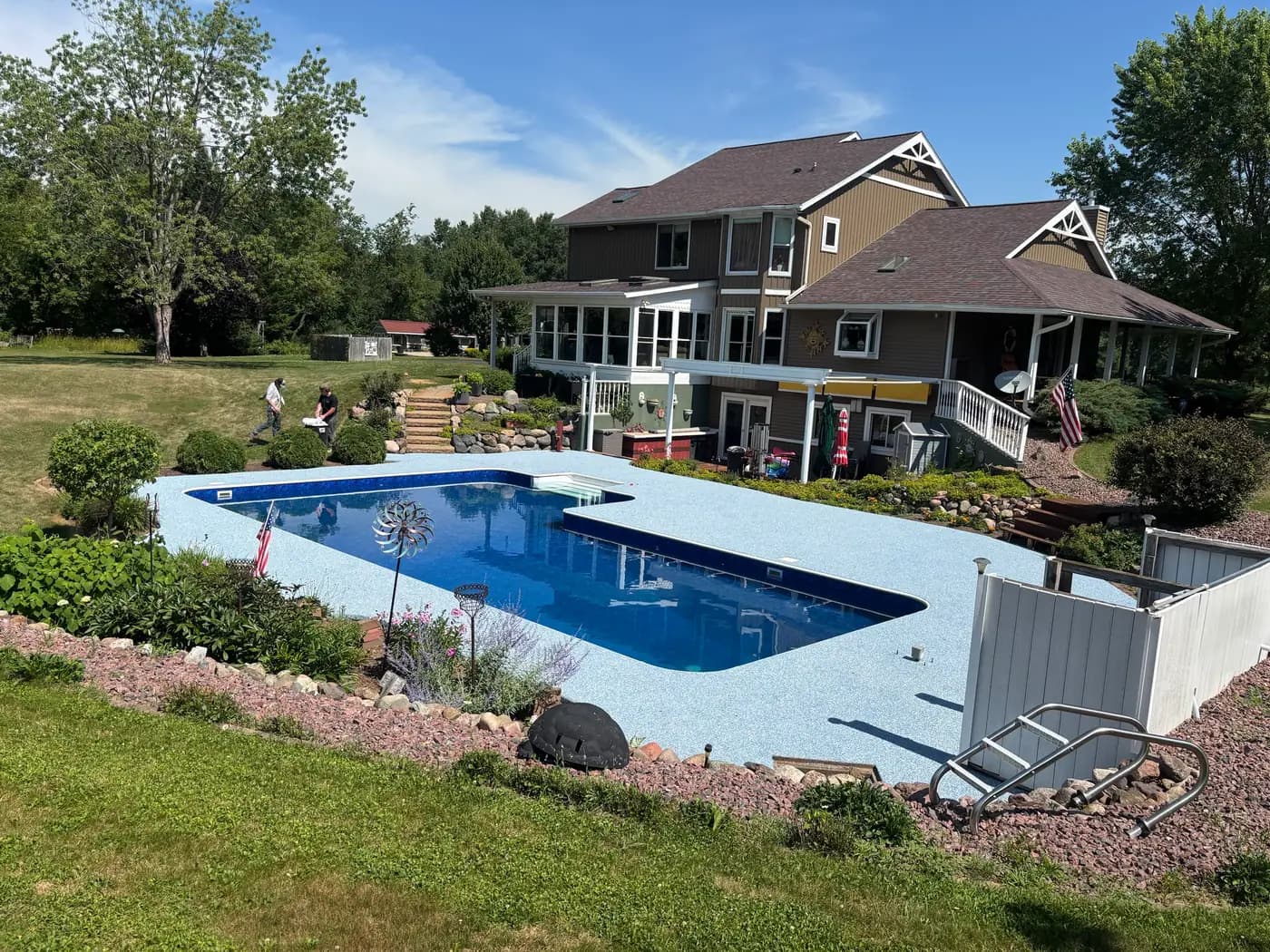Wide view of a light blue RevaFlex pool deck and the house behind it, installed by WAMS