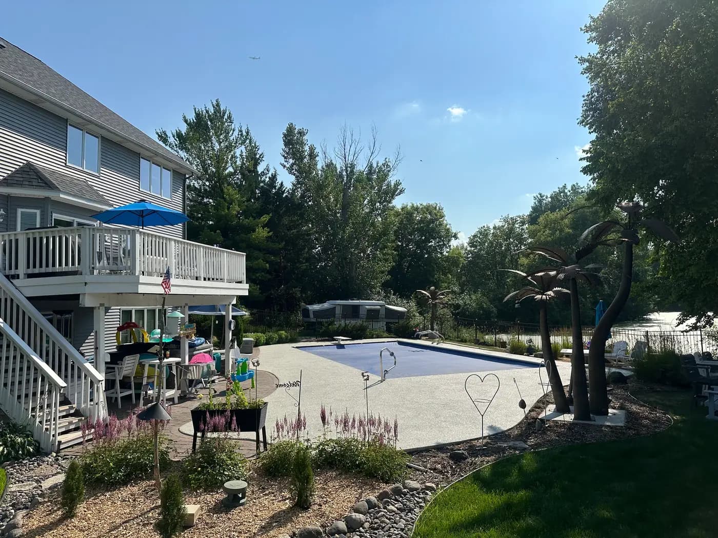 Light gray RevaFlex pool deck curving through a landscaped backyard, installed by WAMS